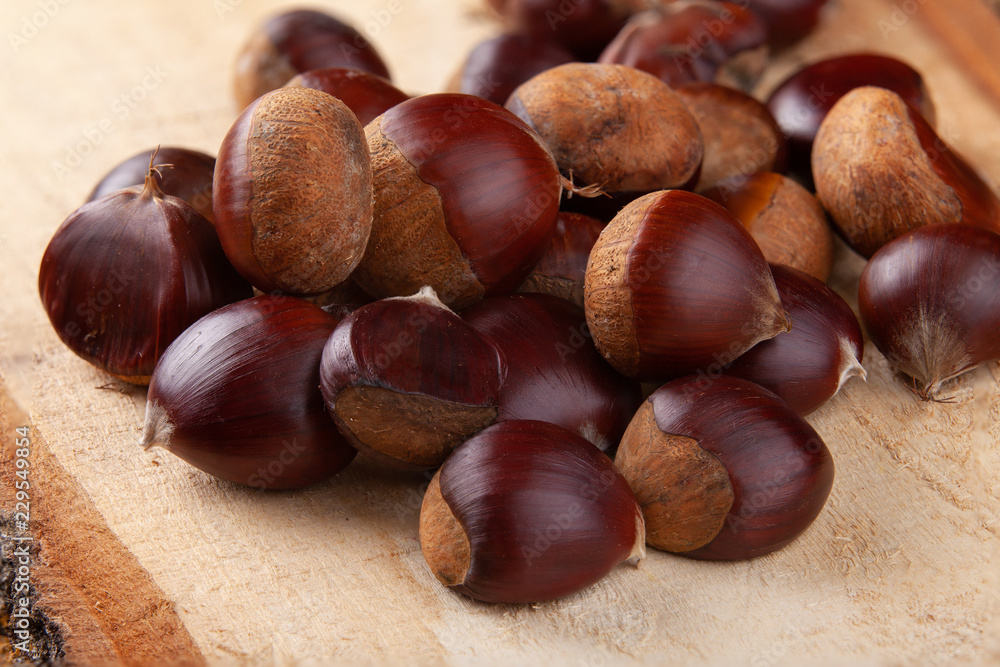Chestnuts on wooden board and autumn leaves Chestnuts on wooden board and autumn leaves
