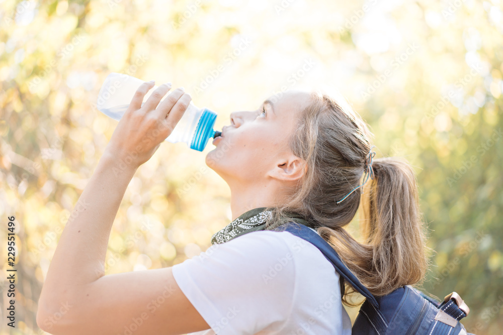 Young beautiful woman drinking water in sport bottle on hiking Young beautiful woman drinking water in sport bottle on hiking