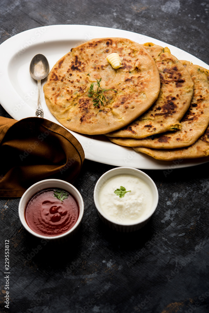 Aloo Paratha / Indian Potato stuffed Flatbread. Served with fresh curd and tomato ketchup. selective focus Aloo Paratha / Indian Potato stuffed Flatbread. Served with fresh curd and tomato ketchup. selective focus