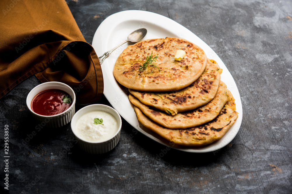 Aloo Paratha / Indian Potato stuffed Flatbread. Served with fresh curd and tomato ketchup. selective focus Aloo Paratha / Indian Potato stuffed Flatbread. Served with fresh curd and tomato ketchup. selective focus