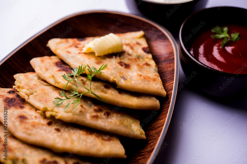 Aloo Paratha / Indian Potato stuffed Flatbread. Served with fresh curd and tomato ketchup. selective focus Aloo Paratha / Indian Potato stuffed Flatbread. Served with fresh curd and tomato ketchup. selective focus