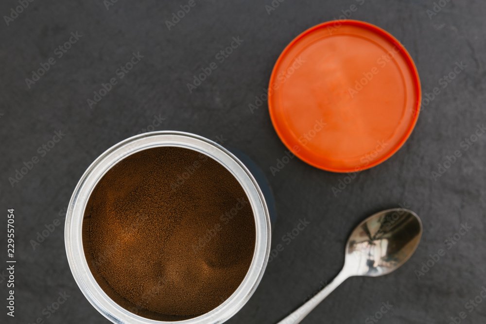 Instant coffee in tin jar spoon on dark background Instant coffee in tin jar spoon on dark background
