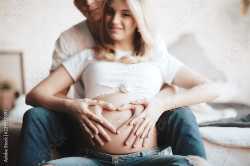 pregnancy concept childbirth and love / man and woman, big belly, hands in the shape of a heart, symbol of pregnancy and love