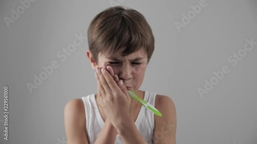 Lttle boy brushing his teeth in bathroom and stop becuse of a tooth pain. Dental problems photo