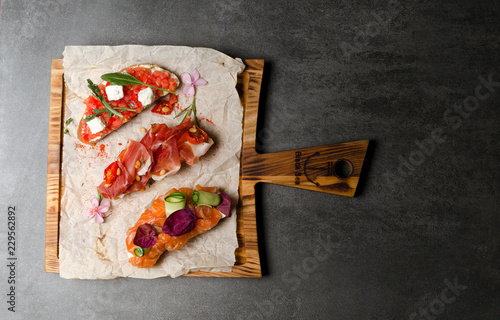 Assorted bruschetta with salmon Parma ham and tomatoes on a wooden board