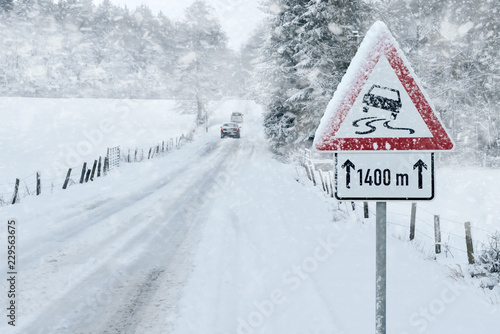 Winter Driving - Snowy Road with Warning Sign 