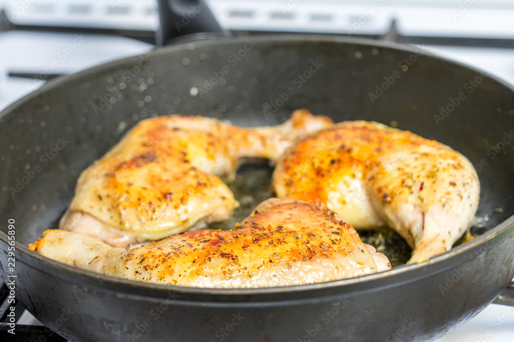Fry chicken legs in a pan with spices.