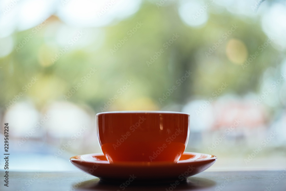 A orange cup of coffee on wooden background in coffee shop