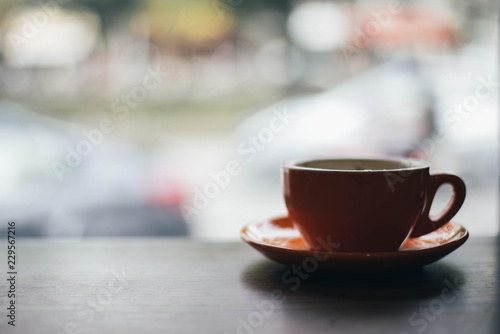 A orange cup of coffee on wooden background in coffee shop