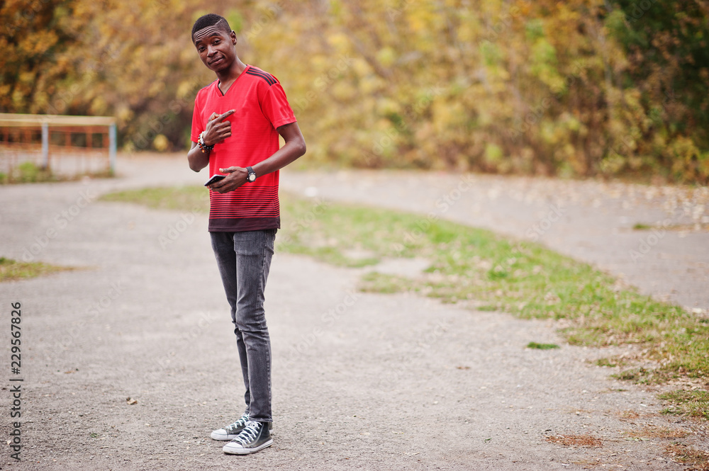 African american man in red football sport t-shirt against autumn park. African american man in red football sport t-shirt against autumn park.