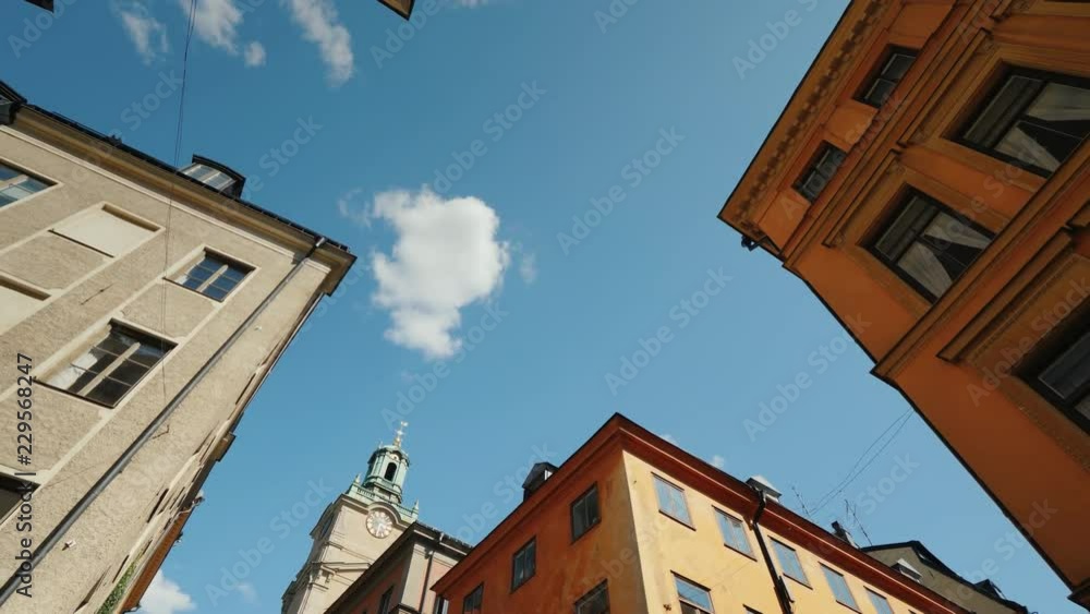 Low angle rotate video St Nicholas - Storkyrkan bell tower in Stockholm. View through a narrow street with old houses Low angle rotate video St Nicholas - Storkyrkan bell tower in Stockholm. View through a narrow street with old houses