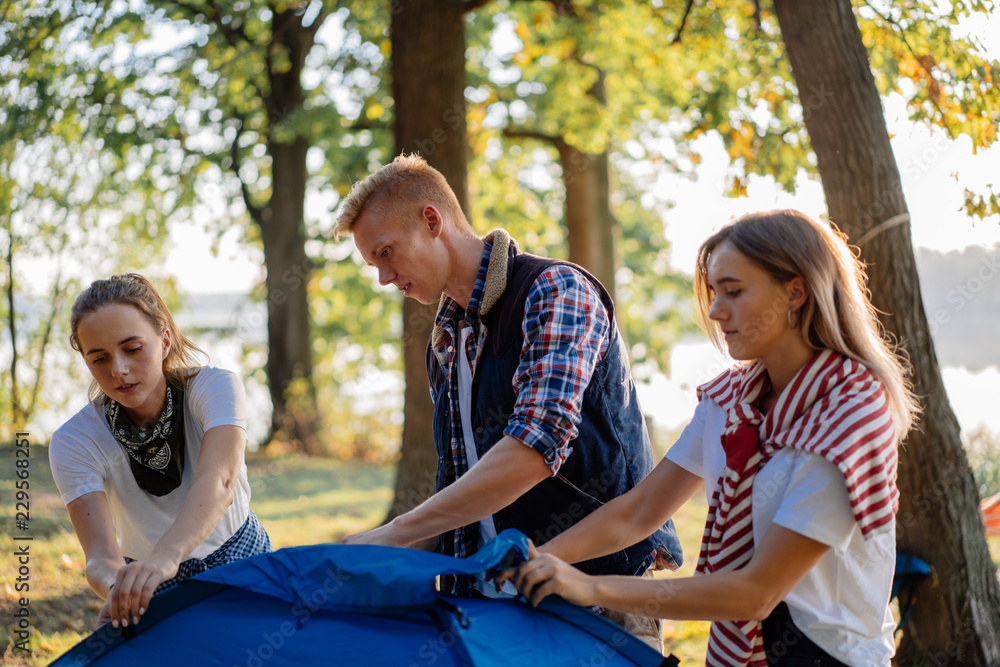 Best friends pitching a tent together on hiking Best friends pitching a tent together on hiking