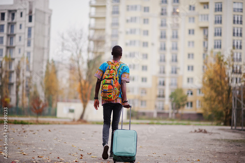 Photography African man in africa traditional shirt on autumn park with backpack and suitcase