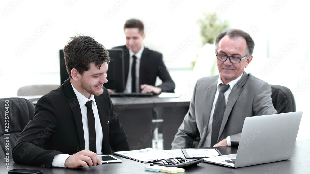 boss and employee discussing the document sitting at the Desk in the office. boss and employee discussing the document sitting at the Desk in the office.