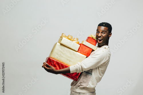 Portrait of an excited young man carrying many gifts , isolated on white studio background