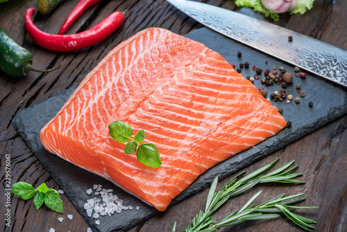 Photos Fresh salmon fillet on black cutting board.