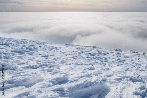 Fresh sparkling snow cover on mountain tops. Cloudy sky at the background.