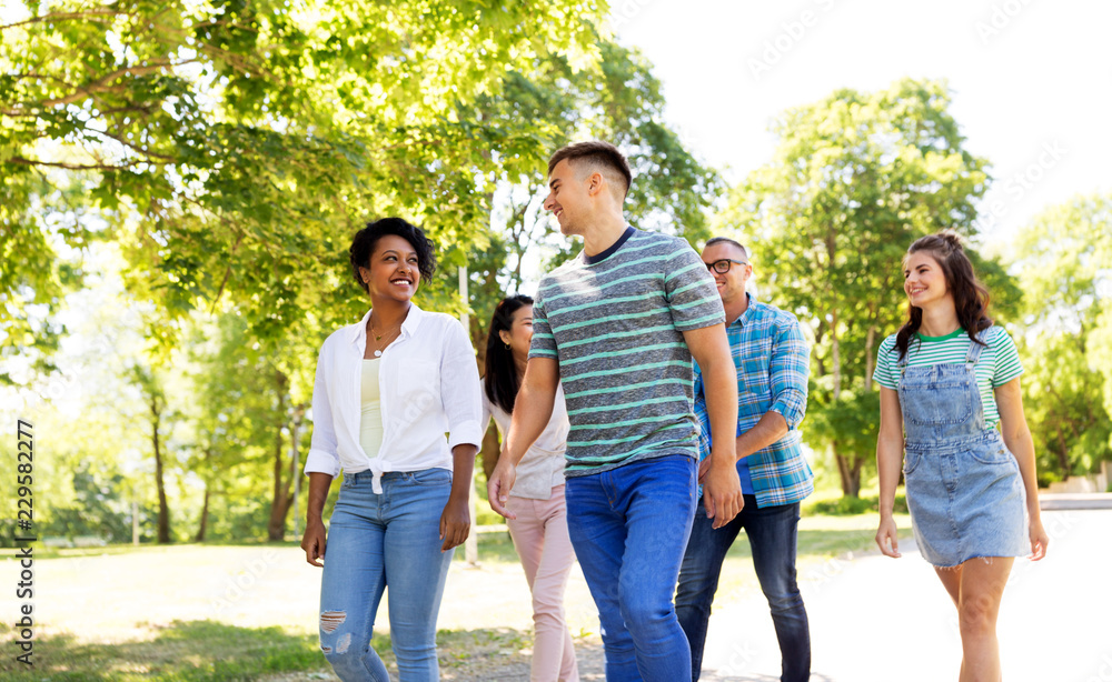 people, friendship and international concept - group of happy friends walking in park people, friendship and international concept - group of happy friends walking in park