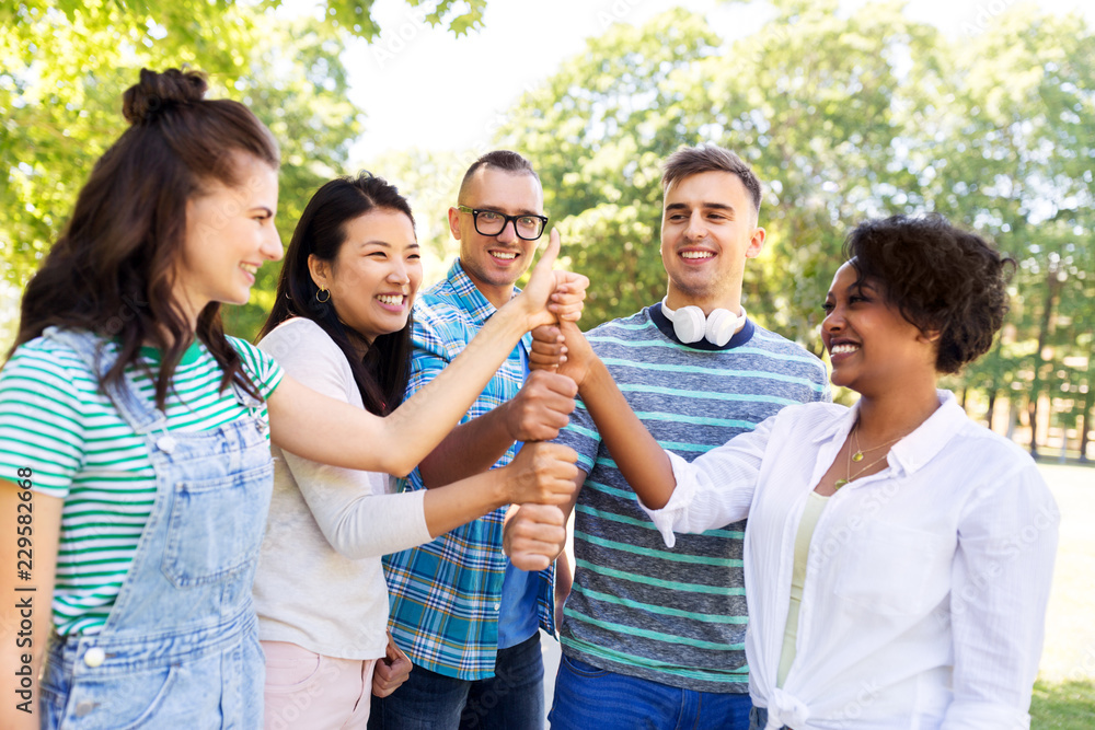 success, friendship and international concept - group of happy smiling friends making thumbs up in park success, friendship and international concept - group of happy smiling friends making thumbs up in park