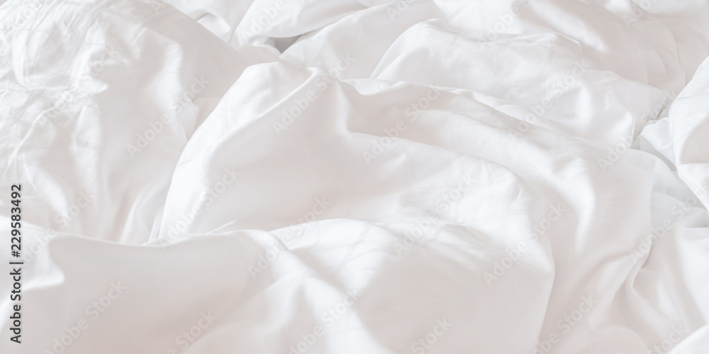 White bed sheet blanket, wrinkled duvet, crumpled comforter cloth used in hotel, resort or home interior for bedding background and sleep comfort White bed sheet blanket, wrinkled duvet, crumpled comforter cloth used in hotel, resort or home interior for bedding background and sleep comfort