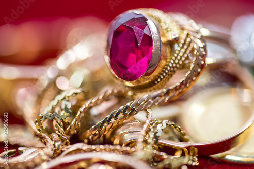 Real gold rings with diamonds, gems, necklace close up shot on red velvet.