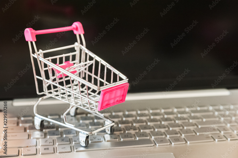 The concept of online shopping. Black Friday. Mini cart from supermarket and laptop, monitor, keyboard, mouse