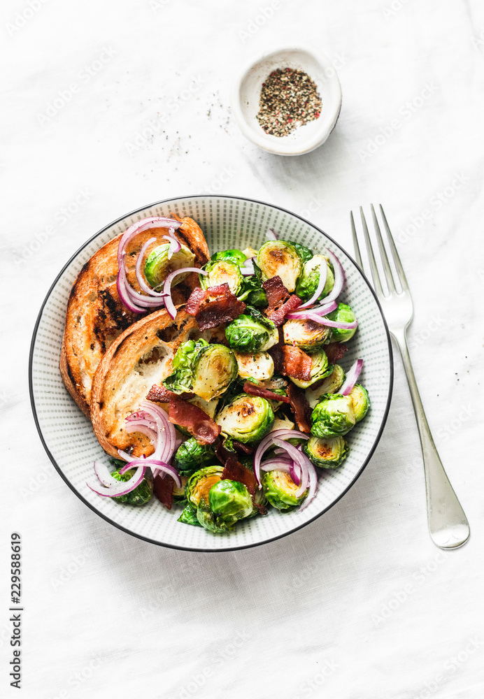 Roasted brussels sprouts with bacon on a light background, top view. Delicious appetizers or snacks Roasted brussels sprouts with bacon on a light background, top view. Delicious appetizers or snacks