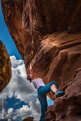 Girl Climber practicing bouldering on a beautiful red rock in Canyonlands Utah USA