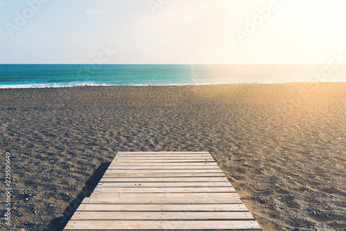 wooden gangplank on beach against sea and blue sky on sunny day
