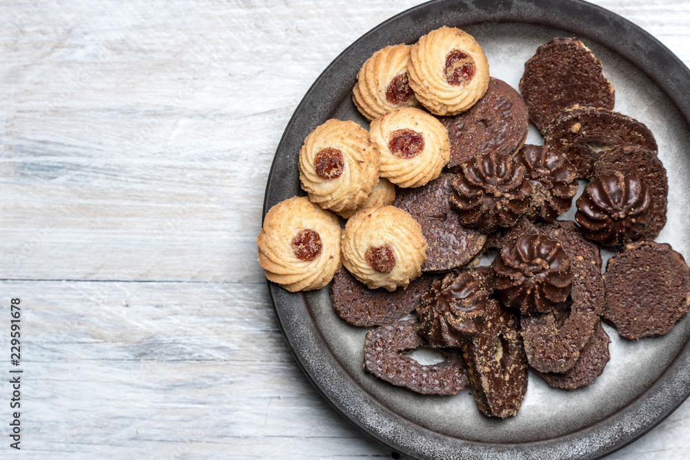 shortbread butter cookies with chocolate and plum jam on a white wooden table