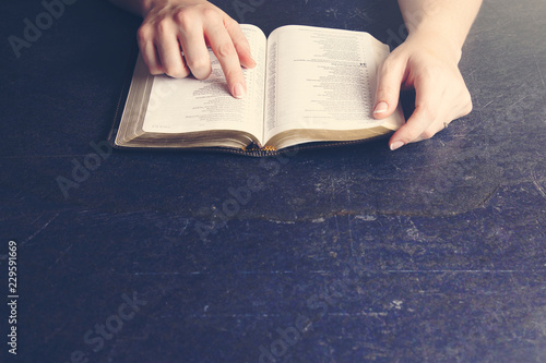 Woman Studying Her Bible on a Dark Table photo