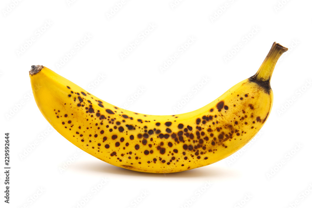 Banana with dark spots with shadow isolated on white background. Closeup, selective focus Banana with dark spots with shadow isolated on white background. Closeup, selective focus
