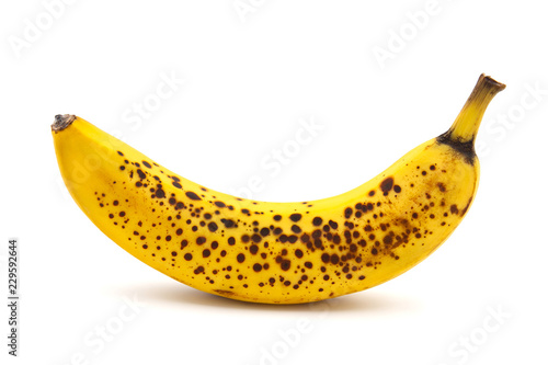 Banana with dark spots with shadow isolated on white background. Closeup, selective focus photo