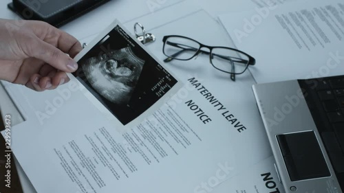 Pregnant Business Woman Looking at an Ultrasound Baby Scan Photo In Office