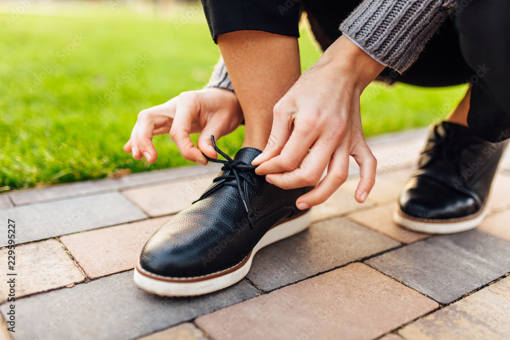 Girl tying shoelaces on moccasins on the street Girl tying shoelaces on moccasins on the street