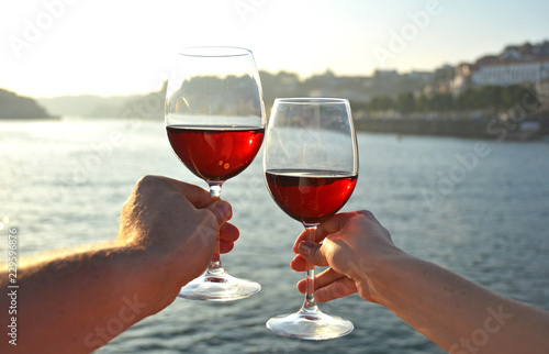 Wine glasses in the hands against Douro river in Porto, Portugal