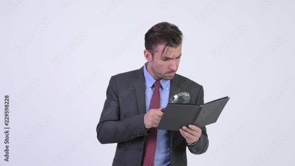 Young Hispanic businessman reading book with magnifying glass Young Hispanic businessman reading book with magnifying glass
