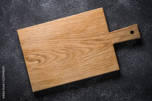 Empty wooden cutting board on black stone table.