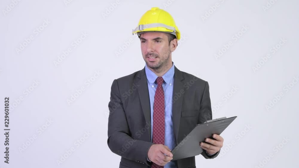 Young Hispanic businessman as engineer reading on clipboard and directing Young Hispanic businessman as engineer reading on clipboard and directing