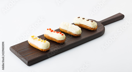 four eclair cakes on wooden board isolated on white background photo