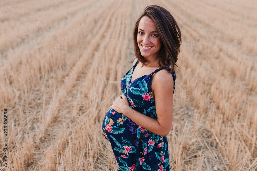 portrait outdoors of a beautiful young pregnant woman in a yellow field. Outdoors family lifestyle. portrait outdoors of a beautiful young pregnant woman in a yellow field. Outdoors family lifestyle.