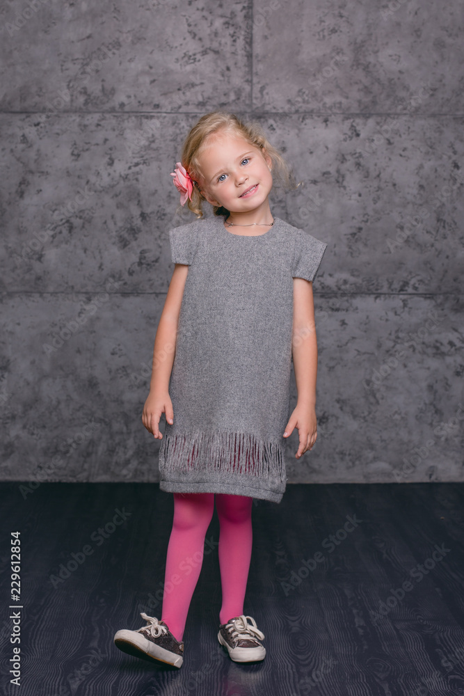 Kid model, girl in a gray dress, flower decoration in a hair Kid model, girl in a gray dress, flower decoration in a hair