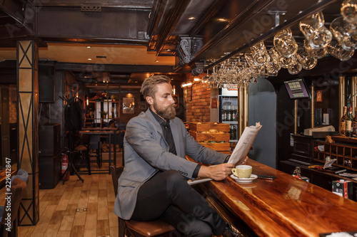 Young bearded businessman reading a newspaper