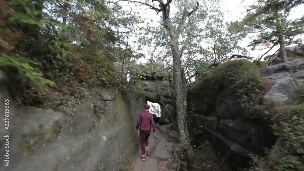 Happy woman runs through a tourist pass among rocks and stones to an observation deck. Tracking shot with stabilized camera Happy woman runs through a tourist pass among rocks and stones to an observation deck. Tracking shot with stabilized camera