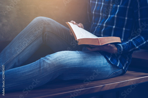 Foto close up of man holding and read bible while sitting on wooden chair, Christian