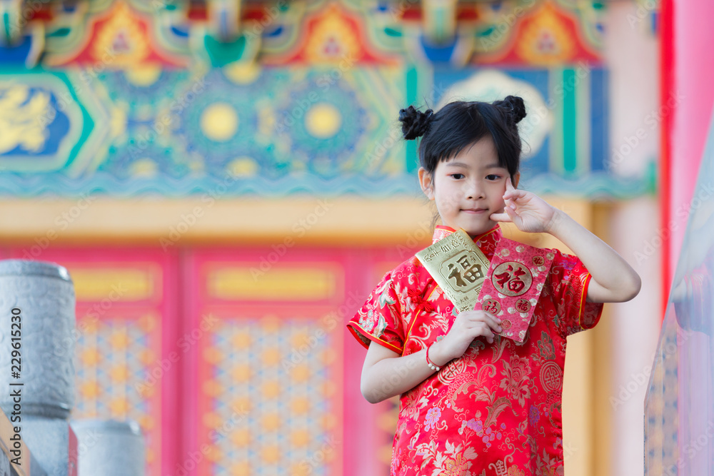 Adorable Chinese girl open golden and red envelopes that contain Chinese word, Xinfu, mean Happiness for Chinese New Year bless Adorable Chinese girl open golden and red envelopes that contain Chinese word, Xinfu, mean Happiness for Chinese New Year bless
