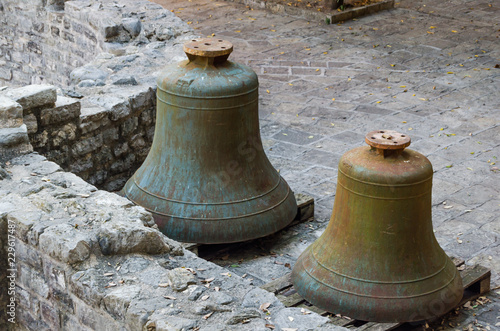 Old and rusty bells lie on stone blocks. photo