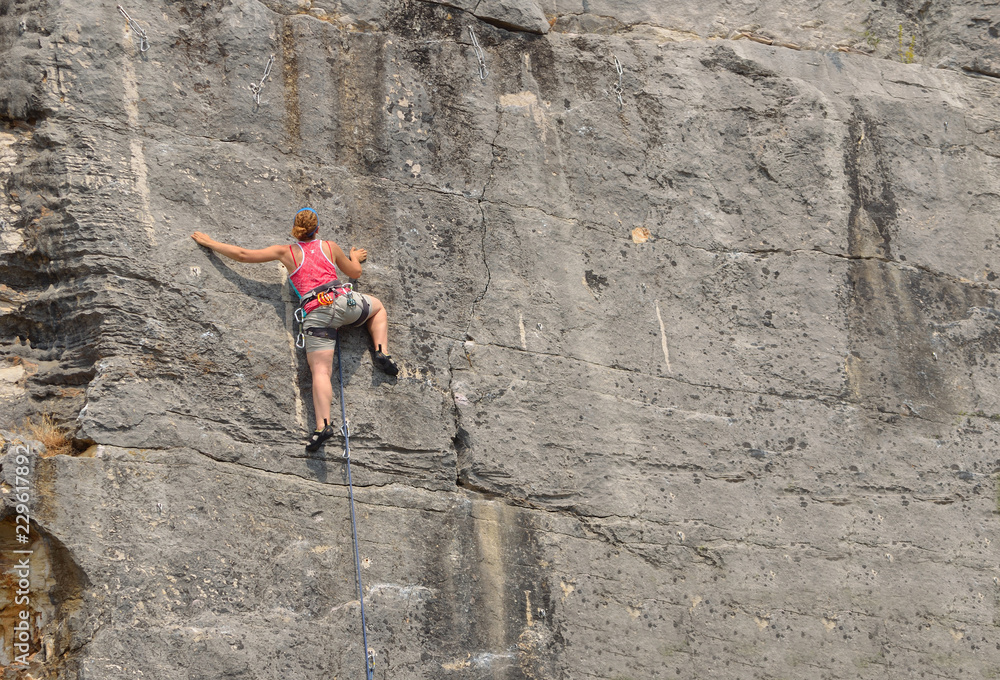 Woman in red top Rock Climbing on Rock Face. Woman in red top Rock Climbing on Rock Face.
