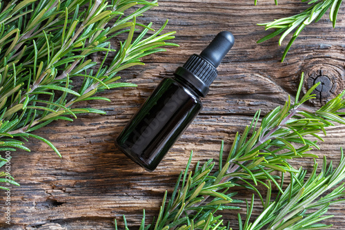 A bottle of rosemary essential oil with fresh rosemary photo