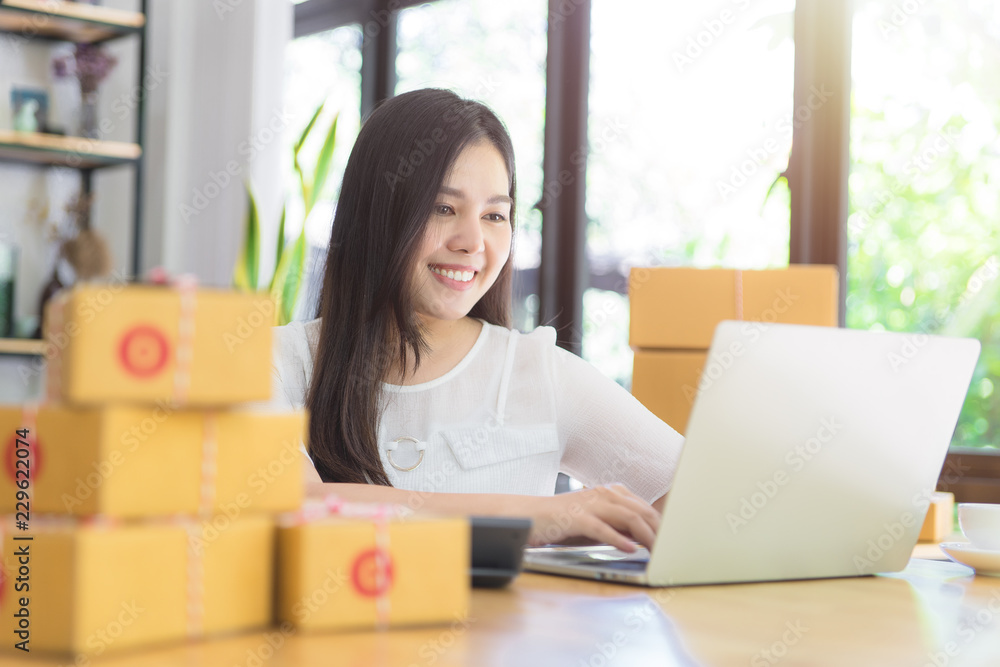 Freelance Asian woman working at home with laptop for online marketing packing box delivery. SME e-commerce online concept. Startup small business concept. Freelance Asian woman working at home with laptop for online marketing packing box delivery. SME e-commerce online concept. Startup small business concept.